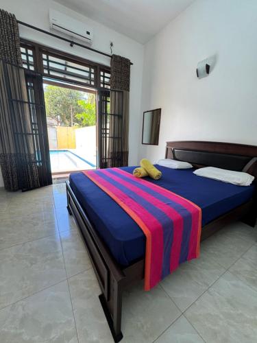 a bedroom with a bed with a colorful blanket on it at Grand Royal Villa Negombo in Negombo