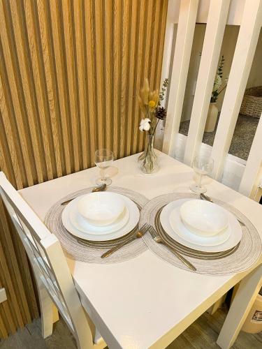 a white table with two plates and glasses on it at La Bella Residences, The Tiny Loft in Tagaytay
