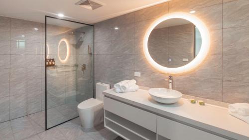 un bagno con lavandino, water e specchio di Hibiscus Suites And Residences a Nadi