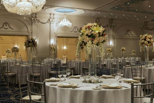a banquet hall with tables and chairs with flowers at The St. Regis New Capital Cairo in Cairo