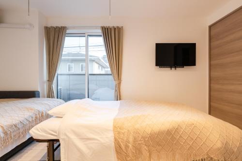 a bedroom with two beds and a tv and a window at House hotel EKODA 202 HE22 in Tokyo