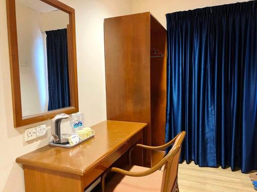 a room with a desk with a mirror and a blue curtain at Northern Lodge Hotel in Sungai Petani