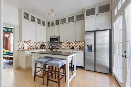 a kitchen with white cabinets and a island with bar stools at Victorian House-30 mins to Napa & SF, Free Pets! in Crockett