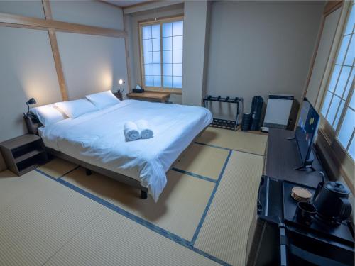 a bedroom with a bed with two towels on it at Welcome Nozawa in Nozawa Onsen