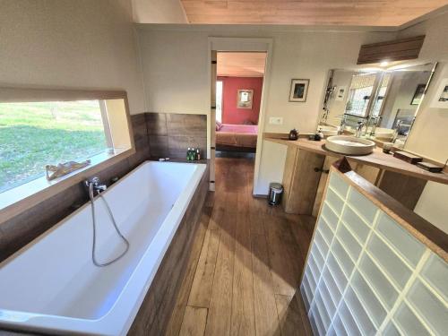 une grande salle de bain avec une baignoire et un lavabo dans l'établissement Maison bois avec piscine privée et Wifi, animaux admis - FR-1-616-447, à Aubas