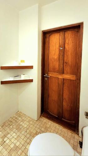 een badkamer met een houten deur en een toilet bij Gingerbread House in El Nido