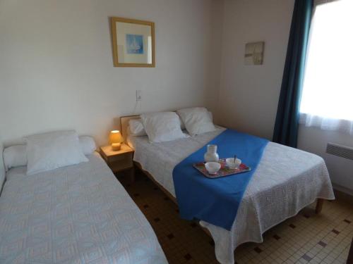 Cette chambre comprend deux lits et une table avec un plateau. dans l'établissement Appartement 39m² pour 5 pers, proche plage, parking, animaux admis - FR-1-540-296, à Notre-Dame-de-Monts