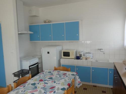 une cuisine avec des placards bleus, une table et un four micro-ondes dans l'établissement Appartement 39m², 1ch, Animaux admis, Parking, Proche plage - FR-1-540-298, à Notre-Dame-de-Monts