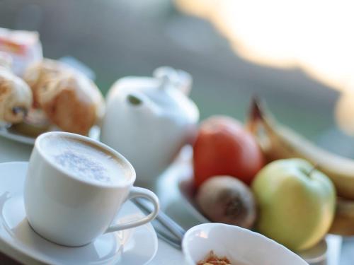 a cup of coffee and a plate of fruit at Hotel Arco Romana in Milan