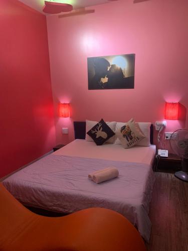 a bedroom with a bed with pink walls and two lamps at KS Tình Nhân Sach Hotel in Ho Chi Minh City