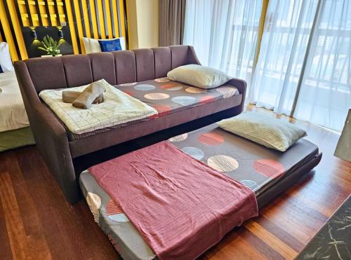 a couch sitting in a living room with two beds at Sunway Studio HomeStay Access Mall & next to Lagoon by Cloud Host in Petaling Jaya