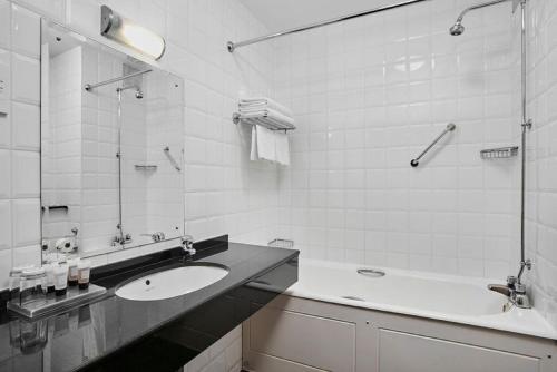 a white bathroom with a sink and a tub at Leonardo Hotel Cheltenham in Cheltenham