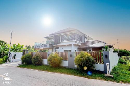 a white house with a fence in front of it at Jazzy Pool Villa Hatyai in Hat Yai