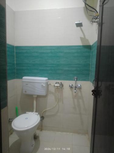 a bathroom with a toilet and a green wall at Moksh Ganga in Rishīkesh