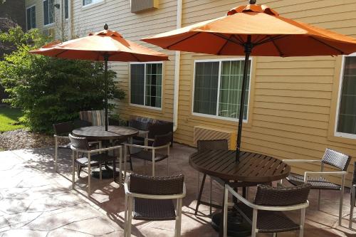 two tables and chairs with umbrellas on a patio at TownePlace Suites Sioux Falls in Sioux Falls