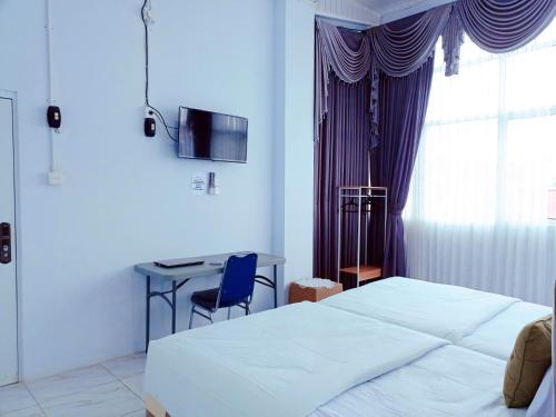 a bedroom with a bed and a desk and a window at Urbanview Hotel at Guest House Bukit Sion Bengkulu in Bengkulu
