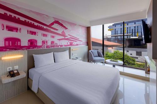 a bedroom with a white bed and a large window at favehotel Hyper Square in Bandung