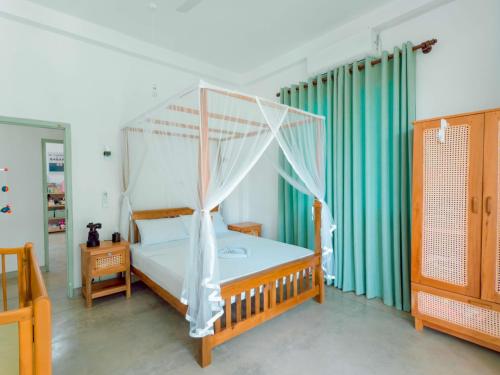 a bedroom with a white canopy bed with green curtains at Villa Ciana- Private apartment in Unawatuna