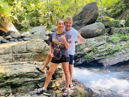 a man and a woman standing on a rock near a river at Palabaddala Tea and Eco Lodge in Ratnapura