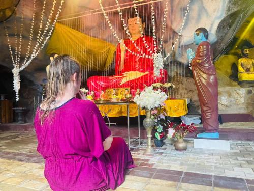 a woman sitting on the ground looking at a statue at Palabaddala Tea and Eco Lodge in Ratnapura