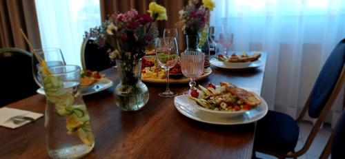 a wooden table with plates of food and wine glasses at Hotel i Restauracja „KRISTAL” in Braniewo