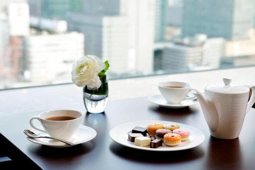 a table with two cups of coffee and a plate of desserts at Yokohama Bay Sheraton Hotel and Towers in Yokohama