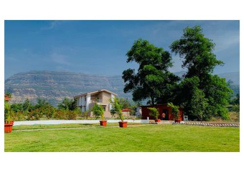 a house in the middle of a field with a tree at Katha Villa 63 - Luxury Holiday Home in Karjat