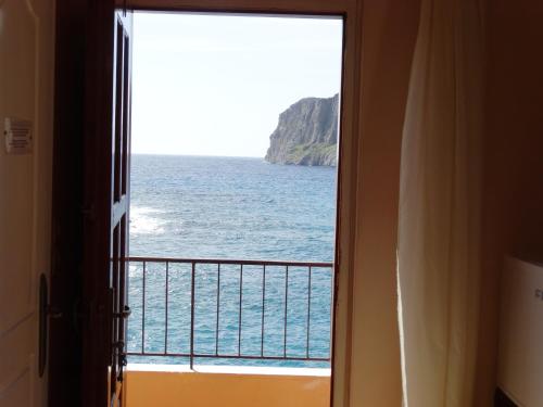 a room with a view of the ocean through a door at Akrotainaritis Rooms in Gerolimenas