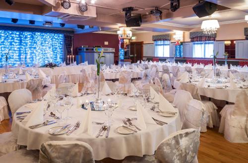 Un salón de banquetes con mesas y sillas blancas. en Lake of Shadows Hotel, en Buncrana