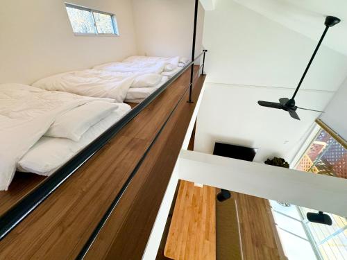 two beds in a room with white walls and wood floors at BBQ可 ワンちゃんok ロフト付き平屋を貸切で楽しむ特別な空間 ハチん家 in Hokuto