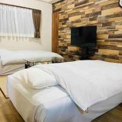 - une chambre avec un lit et une télévision sur un mur en pierre dans l'établissement Alzate Uemachi 301 アルザーテ上町 301, à Osaka