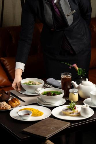 a person standing at a table with plates of food at Mandarin Oriental, Guangzhou in Guangzhou