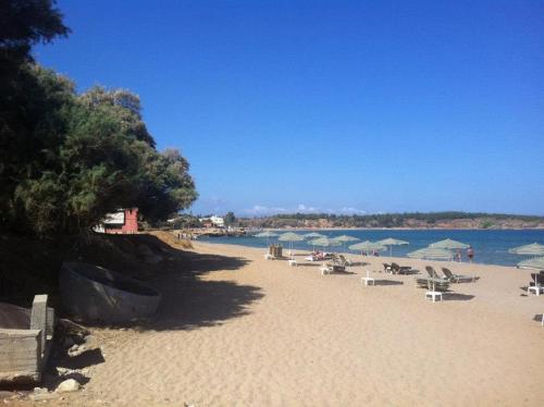 a beach with chairs and umbrellas and the water at Alexis Hotel in Chania Town