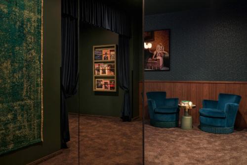 a waiting room with blue chairs and a mirror at Gekko House Frankfurt, a Tribute Portfolio Hotel in Frankfurt/Main