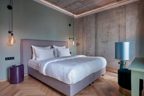a bedroom with a large bed and a blue lamp at Gekko House Frankfurt, a Tribute Portfolio Hotel in Frankfurt/Main