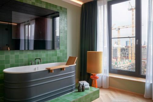 a bathroom with a tub and a window at Gekko House Frankfurt, a Tribute Portfolio Hotel in Frankfurt/Main