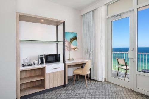 a hotel room with a desk and a balcony at SpringHill Suites by Marriott Panama City Beach Beachfront in Panama City Beach
