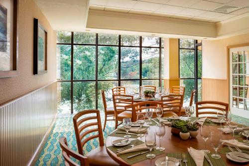 a dining room with a table and chairs and windows at Boston Marriott Newton in Newton