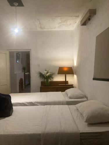 two beds in a bedroom with a lamp on a table at Acacia Inn in Horton Plains
