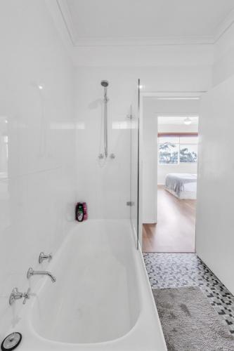 a white bathroom with a tub and a bedroom at Charming Modern Retreat with Scenic View - Burnside in Burnside