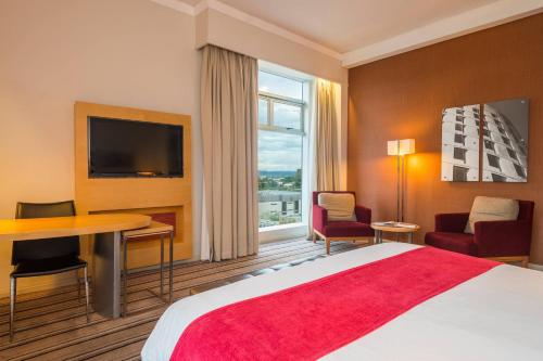 a hotel room with a bed and a desk and a television at Protea Hotel by Marriott Gaborone Masa Square in Gaborone