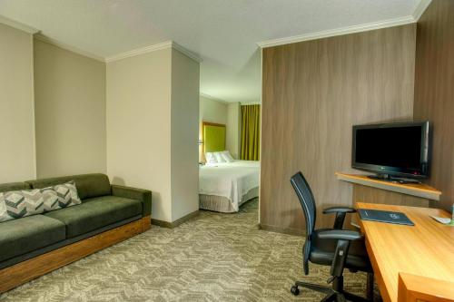 a hotel room with a couch and a bed and a television at SpringHill Suites by Marriott Lawrence Downtown in Lawrence