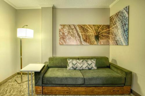 a living room with a green couch and a lamp at SpringHill Suites by Marriott Lawrence Downtown in Lawrence