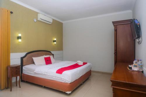 a bedroom with a bed and a desk and a television at RedDoorz Plus near Adisucipto Airport 2 in Yogyakarta