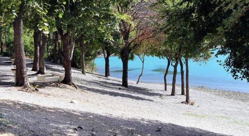 een bankje op een strand naast een waterlichaam bij Apartment Rozman in Vozilići