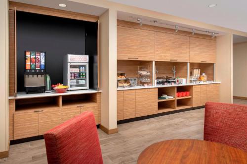 a kitchen with wooden cabinets and red chairs at TownePlace Suites by Marriott College Park in College Park