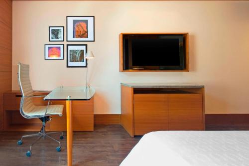 a hotel room with a bed and a desk and a television at Sheraton Hyderabad Hotel in Hyderabad