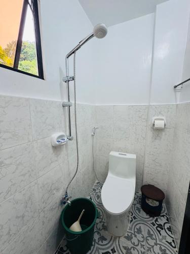 a bathroom with a toilet with a shower and a bucket at Baron Tourist Inn in El Nido