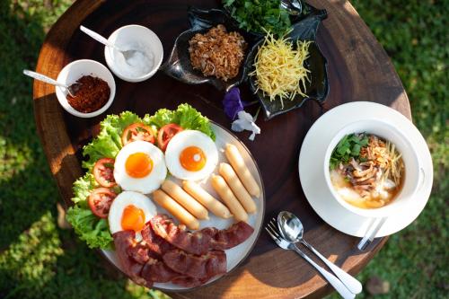 a plate of food with eggs and bacon on a table at Aob Khao Resort and Camping in Ban Pa Lau