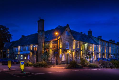 un edificio antiguo por la noche con luz de la calle en The White Hart Royal, Moreton-in-Marsh, Cotswolds, en Moreton-in-Marsh